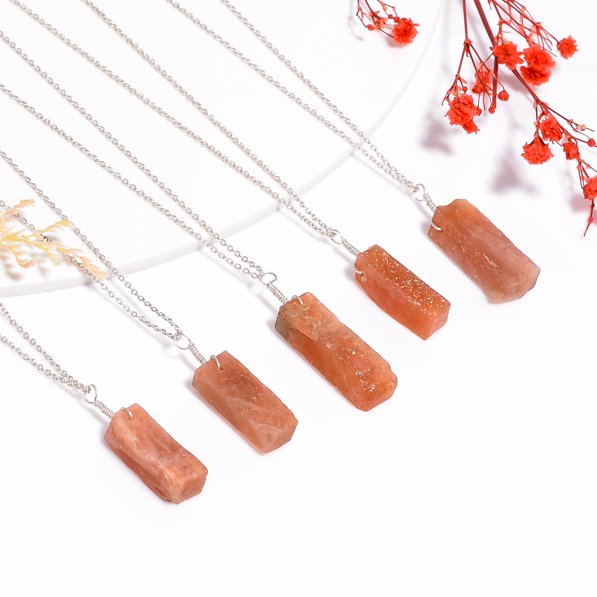 Natural sunstone pendant necklace with raw orange gemstone bar on silver-plated chain in close-up view