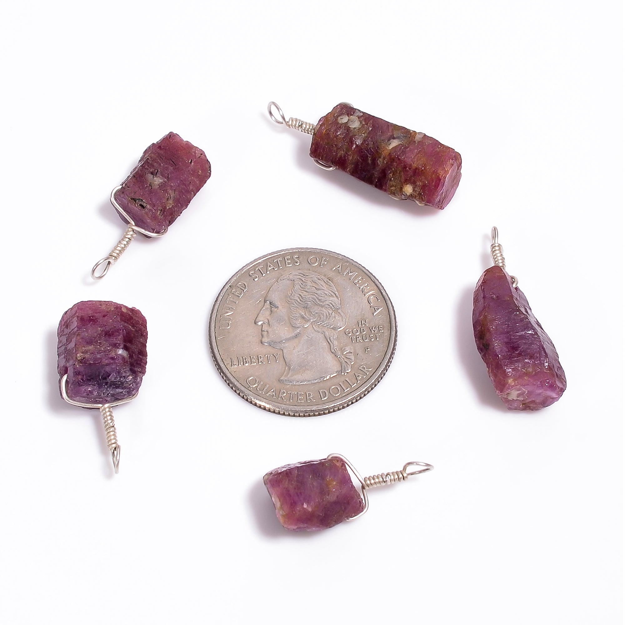 Raw ruby crystal bar pendants shown with a coin for size reference highlighting natural pink color and AA+ quality texture