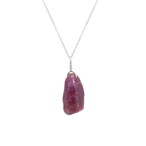 Close-up view of a natural raw ruby crystal pendant on an 18-inch silver-plated chain showcasing vivid pink gemstone
