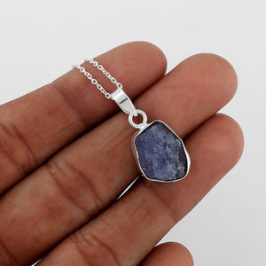 Close-up of real tanzanite raw crystal pendant showing rough blue gemstone texture and polished bezel setting on silver chain