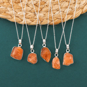 Natural triplite raw crystal pendant necklaces arranged in a row with orange rough stones in bezel settings on silver chain