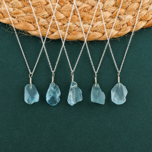 Sky blue topaz raw crystal pendant necklaces arranged in a row showing irregular gemstone shapes on silver-plated chains