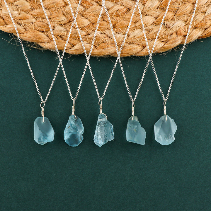 Sky blue topaz raw crystal pendant necklaces arranged in a row showing irregular gemstone shapes on silver-plated chains