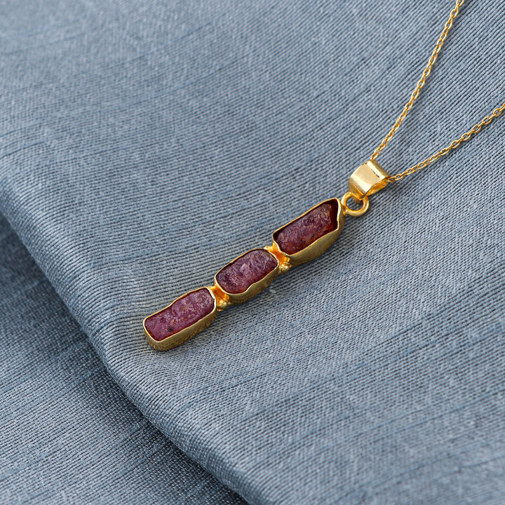 Natural ruby raw crystal pendant necklaces arranged in a row with pink irregular stones set in gold-plated bezels on 18-inch chains