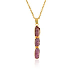 Raw ruby crystal pendant necklace in gold-plated bezel setting displayed on white background showing delicate pink gemstone