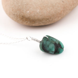 Turquoise stone necklace on a white background with a stone in the background