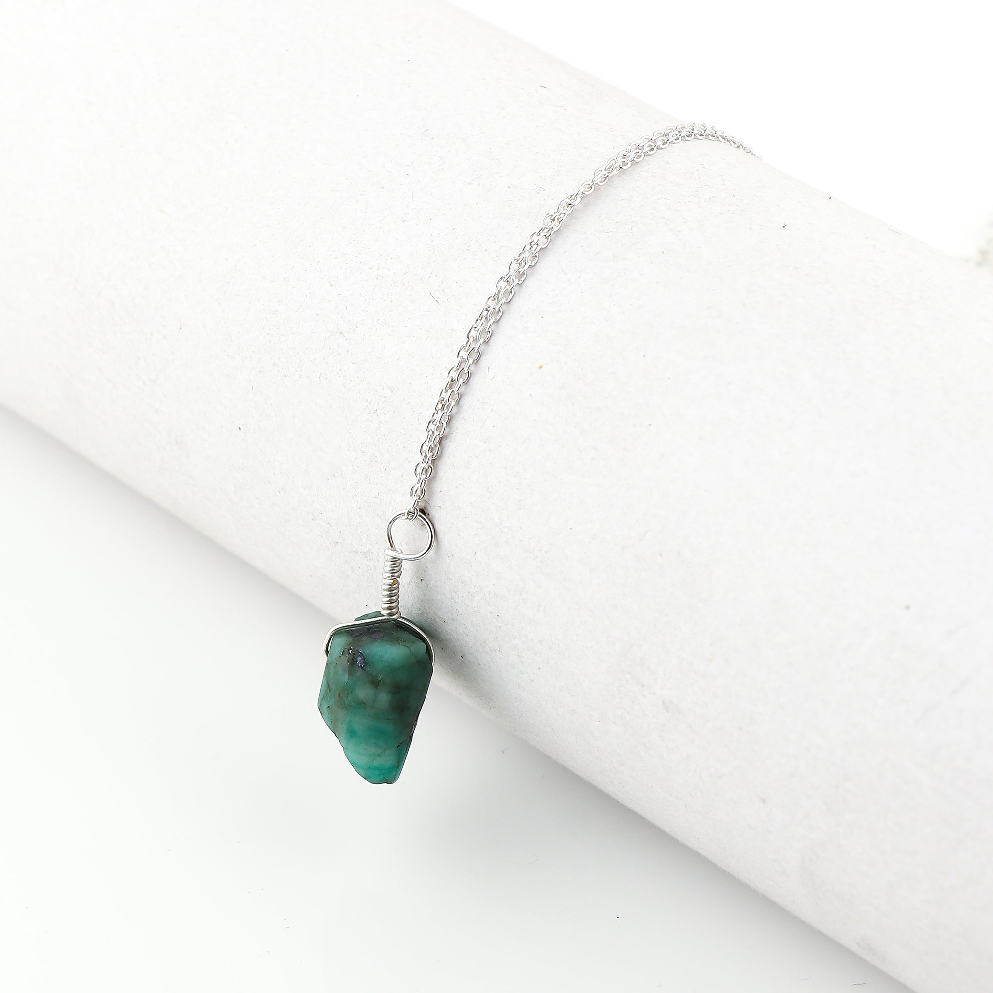 Natural raw emerald crystal pendant necklaces arranged in a row showing vibrant green irregular stones on silver-plated 18-inch chains
